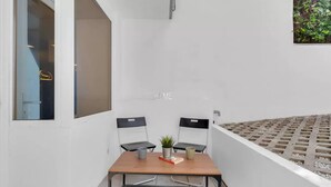 A room with a white wall, a window, a table with two chairs, a potted plant, and a small table. - MA6 [Cathedral] • Spacious luxury apartment in a central location • (Milano)