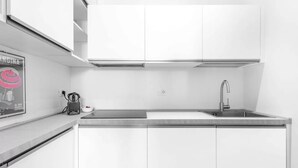 Une cuisine moderne avec des meubles blancs, un évier en acier inoxydable et un plan de travail noir.
