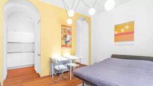 Une chambre à coucher avec un lit, un bureau avec des chaises, une armoire blanche et un tableau accroché au mur.