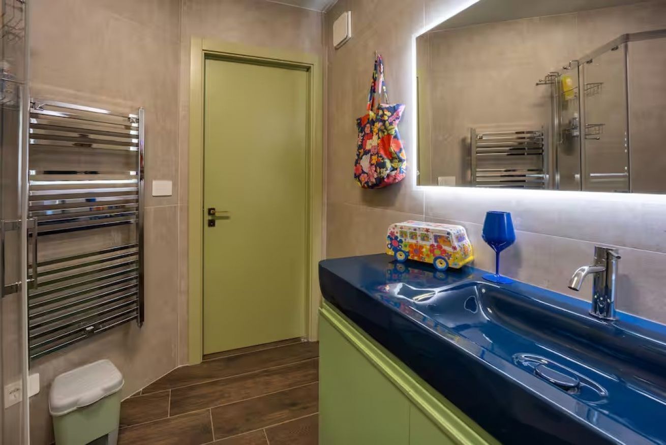Une salle de bain avec un lavabo, un miroir, un porte-serviettes et une porte.