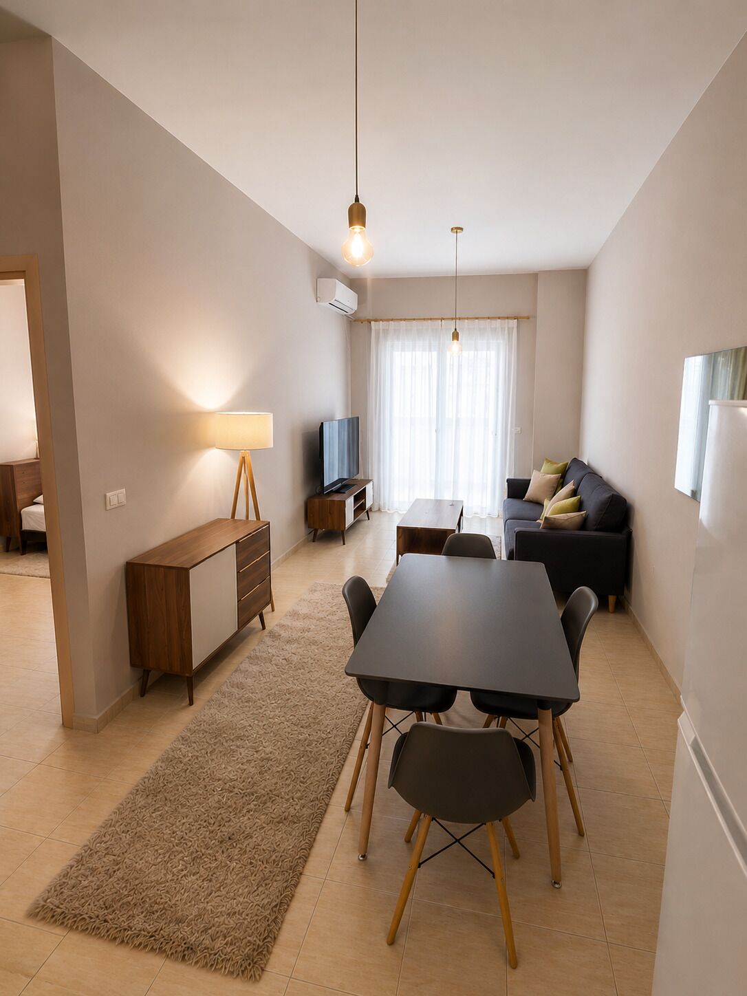 Ein modernes Wohnzimmer mit einer Couch, einem Fernseher, einem Esstisch und einer Lampe.