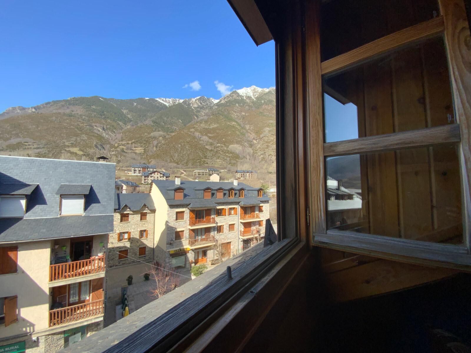 A mountain view with a building featuring balconies and a stone facade.