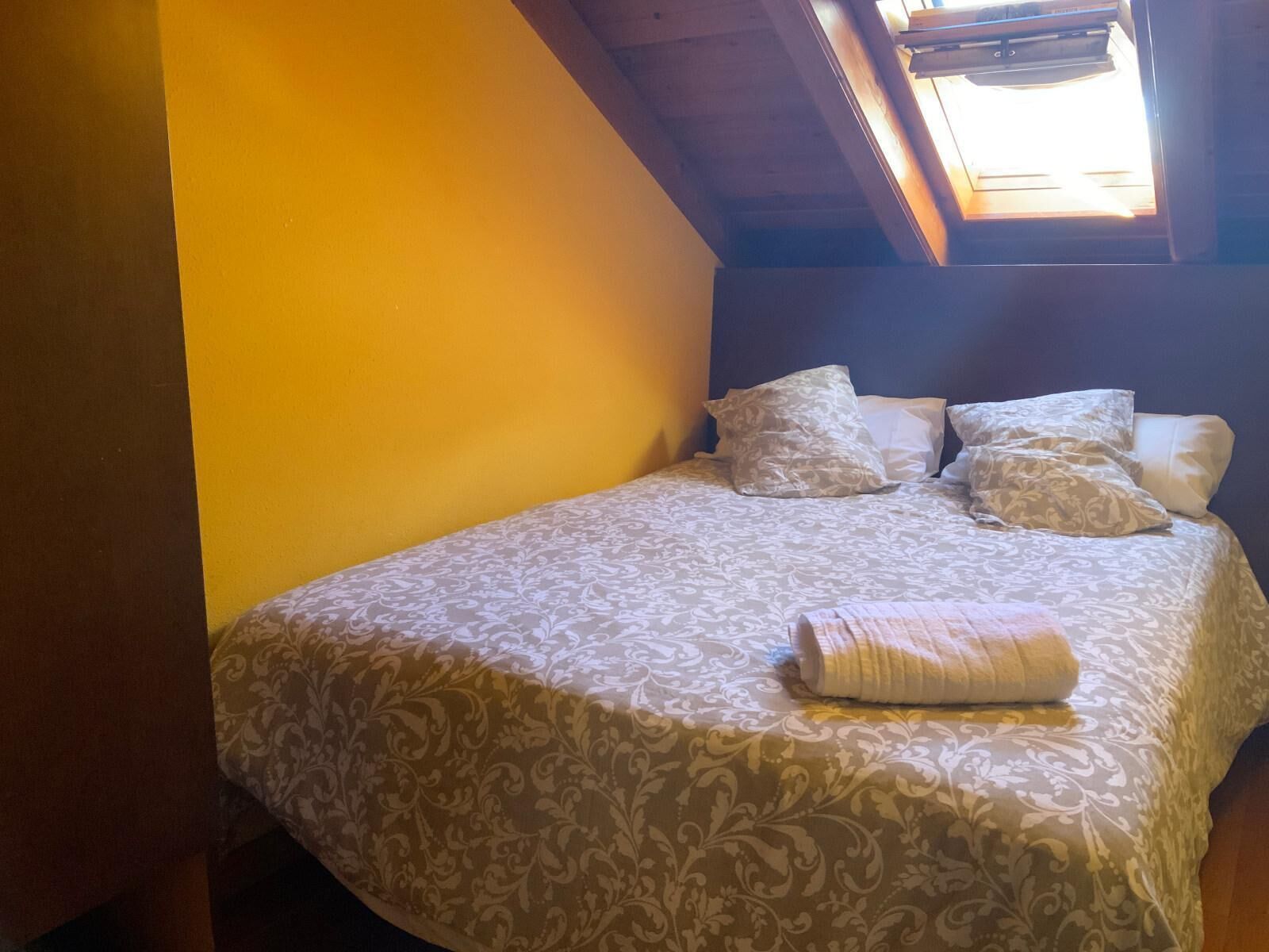 Ein Schlafzimmer mit einem Bett, Kissen und einem Oberlicht.