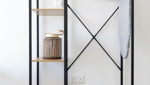 Un mueble de madera con estantes y espacio para colgar, un archivador pequeño y un enchufe en la pared.