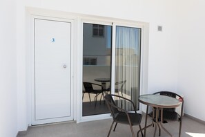 Ein Balkon mit einer Schiebetür aus Glas, einem Tisch und zwei Stühlen.