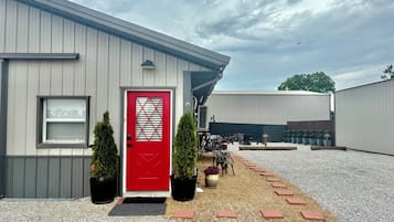 A building with a red door, a window, and a gravel driveway with stepping stones.