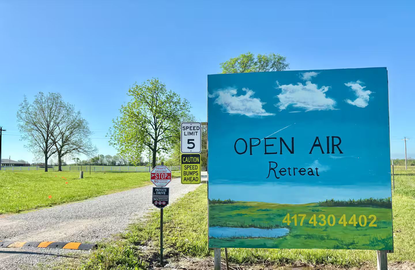 Bordje voor Open Air Retreat met een telefoonnummer, een maximumsnelheid bord en een waarschuwing voor een privéoprit.