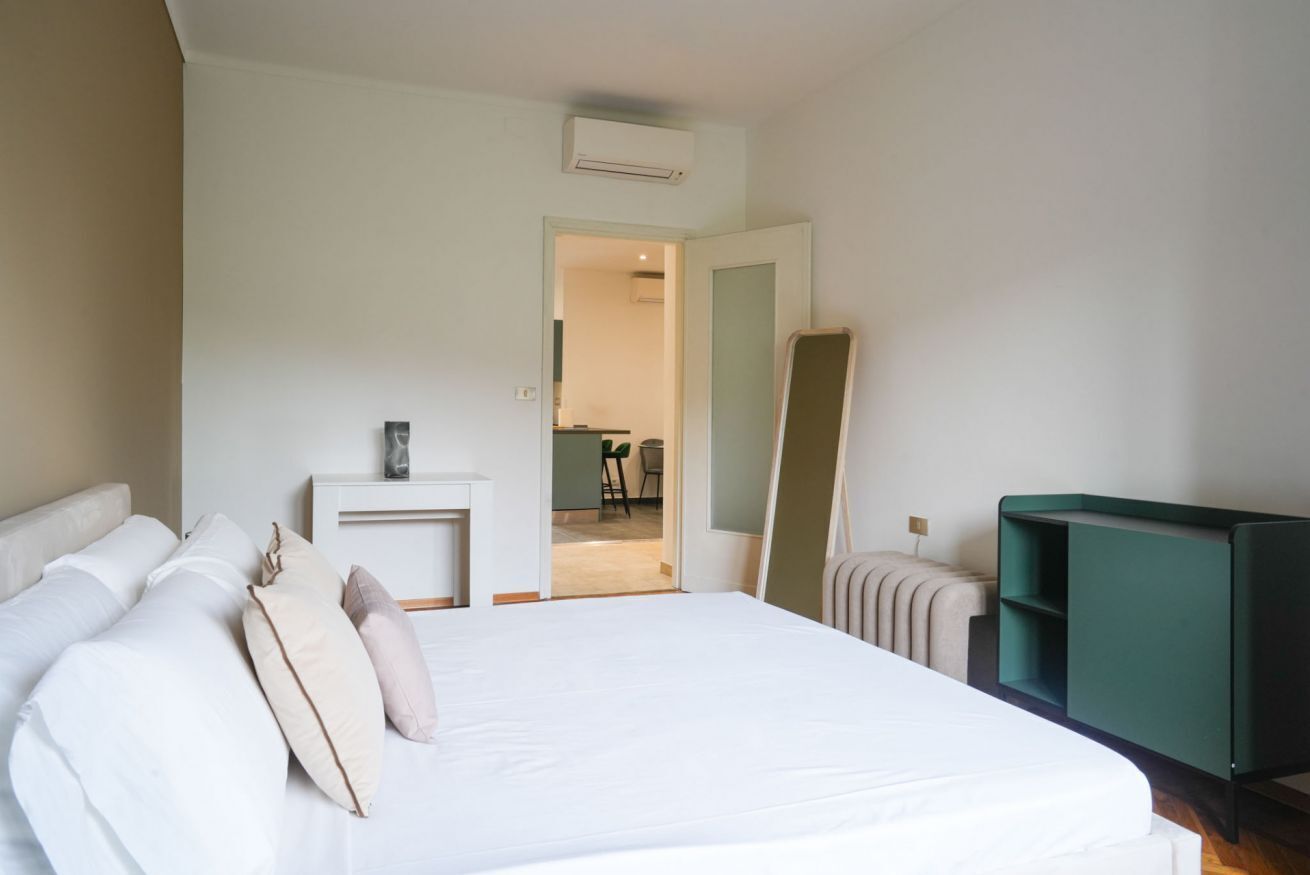 A bedroom with a bed, bedside table, dresser, and a mirror.