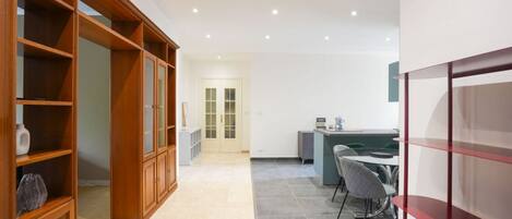 A hallway with a wooden cabinet, a desk with a chair, and a door in the background.