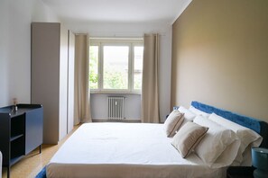 Ein Schlafzimmer mit Bett, Schreibtisch und einem fenster mit Vorhängen.
