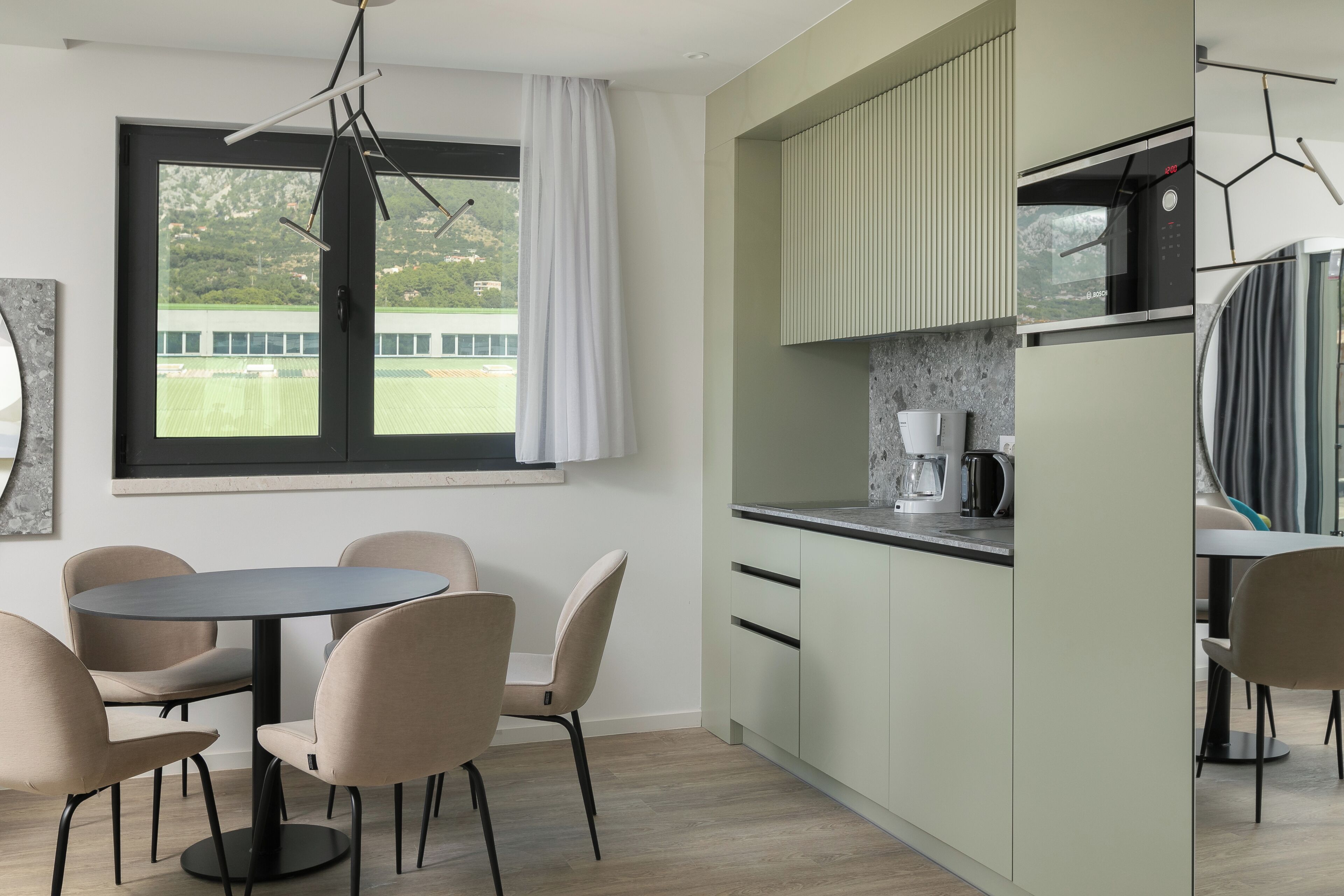 Una cocina moderna con comedor, un ventanal con vistas a un campo deportivo y un horno empotrado.