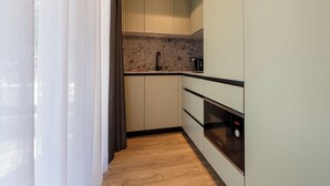 Una cocina compacta con horno integrado, un lavamanos y una encimera.