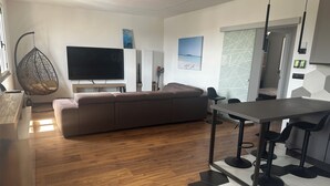 En moderne stue med en stor sofa, et spisebord og et fjernsyn.