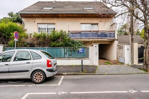 A residential building with a garage entrance, a parked car, and a no parking sign. - Cozy Studio - CDG - Exhibition Center - ARENA Grand Paris (Sevran)