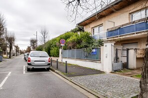 A residential street with parked cars, a no parking sign, and a gated entrance to a building. - Cozy Studio - CDG - Exhibition Center - ARENA Grand Paris (Sevran)