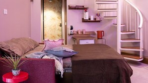 A bedroom with a bed, a desk, a chair, a red side table, and a staircase. - ADA'S P By Dimorra  (Napoli)