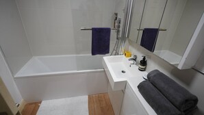 Un baño moderno con bañera, lavabo, espejo y ducha.