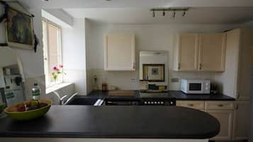 A kitchen with white cabinets, a black countertop, a microwave, and a sink.