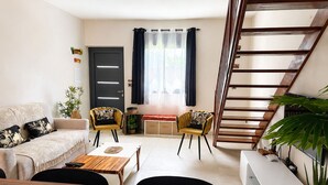 A living room with a sofa, two chairs, a coffee table, a staircase, and a door. - Apartment mountain view, AC - 2 guests (Bras-Panon)