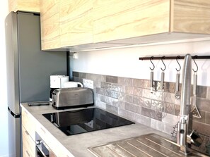 A kitchen with a built-in toaster, a coffee maker, and a sink with hanging utensils. - House with stunning sea view - 2 guests (Groix)
