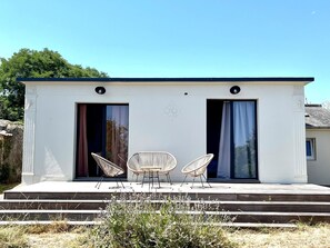 A modern building with two open doors, a small outdoor seating area with two chairs, and a clear sky. - House with stunning sea view - 2 guests (Groix)
