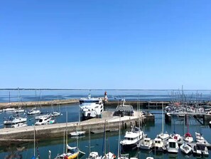 A marina with multiple boats docked, a lighthouse in the background, and a clear blue sky. - House with stunning sea view - 2 guests (Groix)