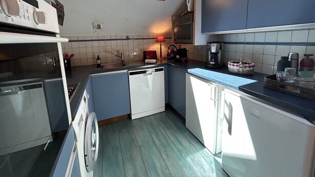 A compact kitchen with a skylight, built-in appliances, and a tiled backsplash. - Apartment in Méribel, mountain view - 8 guests (Méribel)