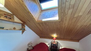 A small room with two single beds, a skylight, a table with a lamp, and a teddy bear. - Apartment in Méribel, mountain view - 8 guests (Méribel)