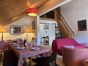 Ein Essbereich mit Tisch für vier Personen, einer Treppe und einem rot bezogenen Sofa.