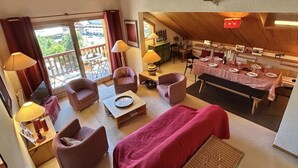 A cozy room with a dining area, a sofa, and a table set for a meal. - Apartment in Méribel, mountain view - 8 guests (Méribel)