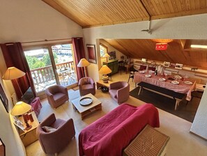 Ein gemütliches Zimmer mit Essbereich, einer Couch und einem für eine Mahlzeit gedecktem Tisch.