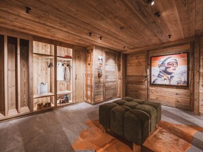 A wooden interior with a sofa, a TV, and a clothing rack. - Chalet with Mont-Blanc view - 4 guests (Chamonix-Mont-Blanc)
