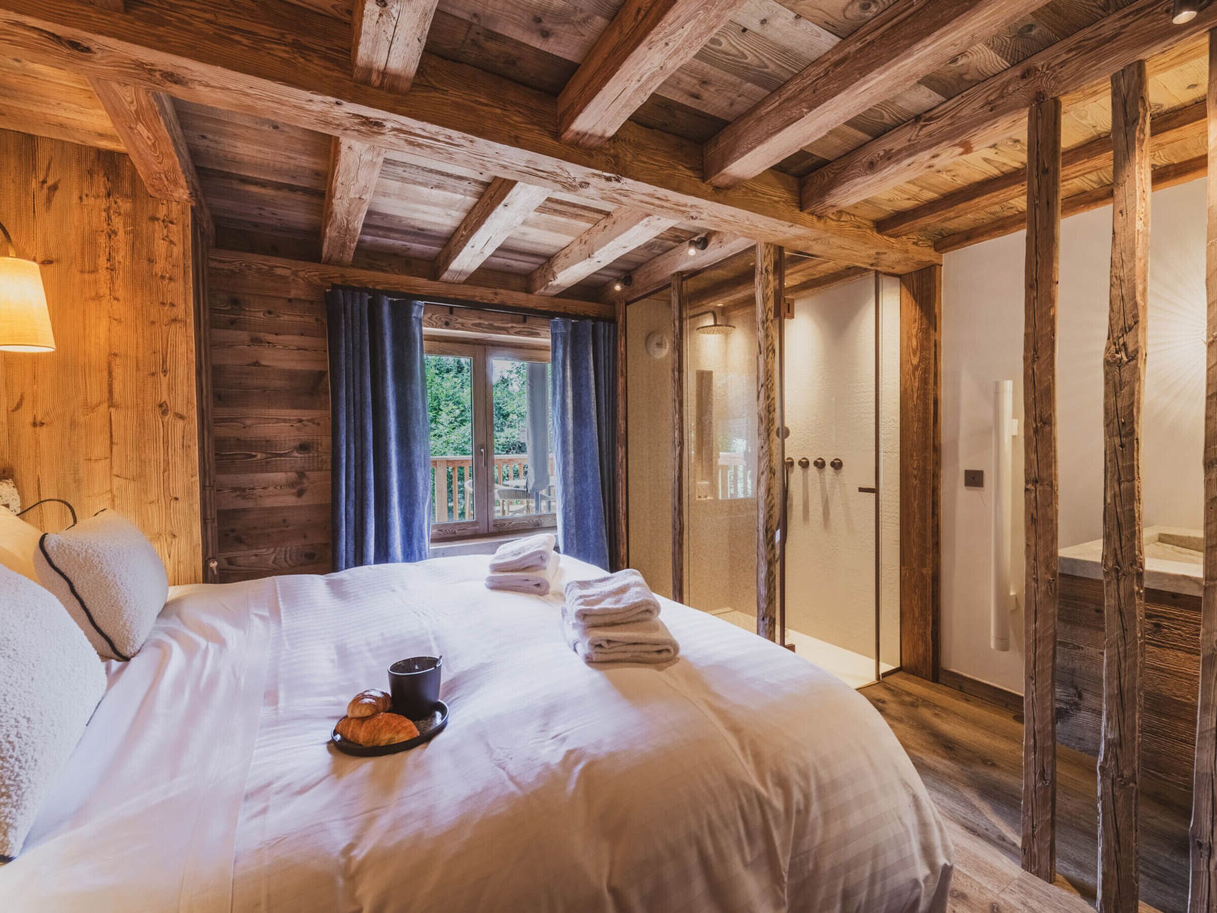 Une pièce en bois avec un lit, une fenêtre avec des rideaux et une porte.