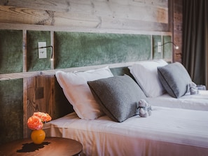 Ein Schlafzimmer mit einem hölzernen Kopfteil, weißer Bettwäsche und einem kleinen Tisch mit einem Blumenvasen.
