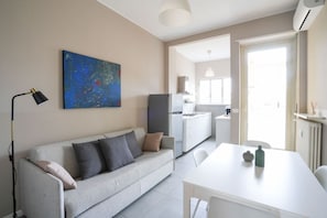 A modern living room with a sofa, a table, and a kitchen area in the background. - Torino Centro | Casa Regina (Torino)