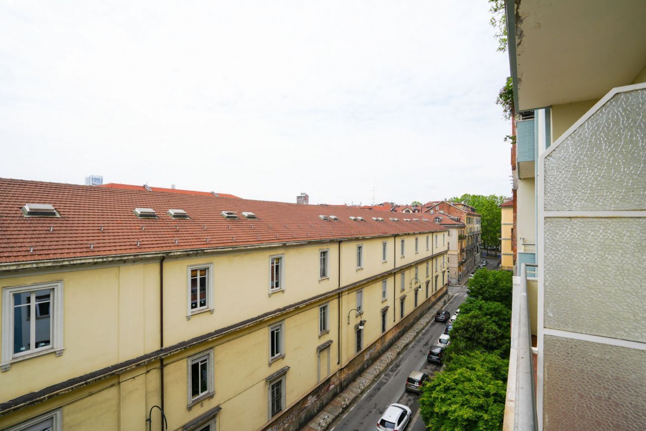 A row of yellow buildings with red tiled roofs and a street in between.
