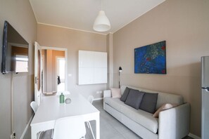 A modern living room with a sofa, a dining table, and a painting on the wall. - Torino Centro | Casa Regina (Torino)