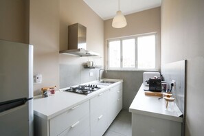 A modern kitchen with white cabinetry, a gas stove, a built-in oven, and a window providing natural light. - Torino Centro | Casa Regina (Torino)