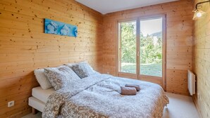 Una habitación con paneles de madera, una cama, una ventana y un cuadro en la pared.