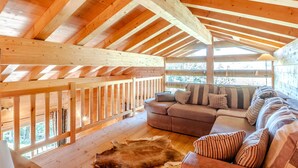 Una cabaña con interior de madera, un sofá y una alfombra de piel.