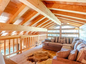 Eine Hütte mit Holzvertäfelung, einem Sofa und einem Fellteppich.