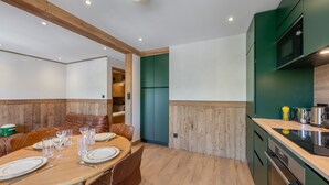 Une cuisine moderne avec des meubles en bois, une table à manger pour quatre personnes et un four encastré.