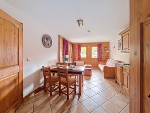 A wooden interior with a dining table, chairs, a sofa, and a kitchen area.