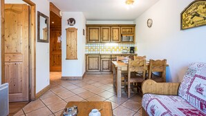 Uma cozinha com armários de madeira, uma mesa de jantar com cadeiras, uma máquina de café e um relógio na parede.