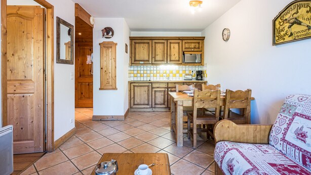 Una cucina con mobili in legno, un tavolo da pranzo con sedie, una macchina da caffè e un orologio a parete.