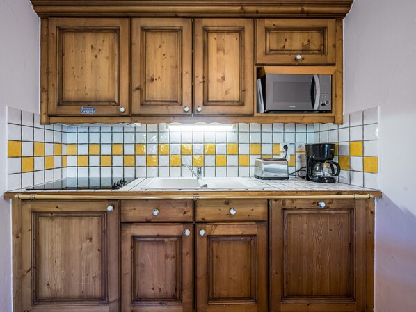 Eine Küche mit Holzausstattung, einer Mikrowelle, einem Toaster und einer Kaffeemaschine.
