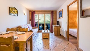 Una camera accogliente con pavimento in legno, un divano, un tavolo da pranzo con sedie, una piccola credenza e un letto.