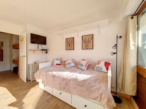 Ein Schlafzimmer mit einem Bett, einem Nachttisch, einem Fernseher und Kunstwerken an der Wand.