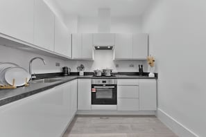 A modern kitchen with white cabinetry, a stainless steel sink, and a built-in oven.