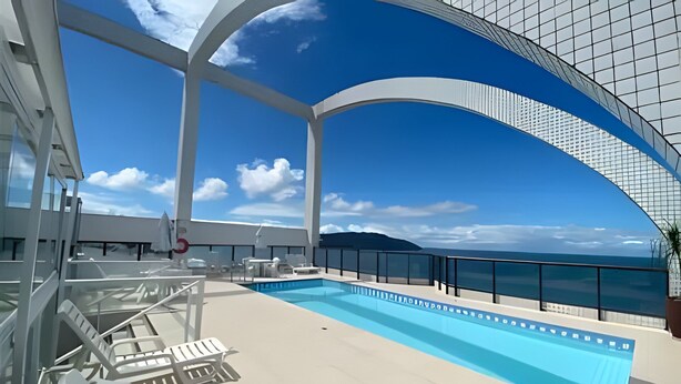 A pool area with lounge chairs and a clear view of the ocean. - SHB Magia de uma Vista Panorâmica (Santos)